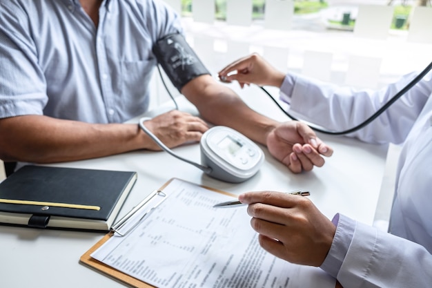 Doctor using stethoscope checking measuring arterial blood pressure on arm to a patient in the hospital.