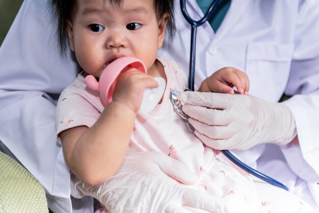 A doctor using a stethoscope checking the respiratory system and heartbeat of baby newborn