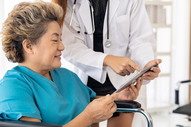 Doctor using tablet with old patient