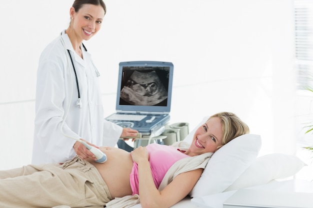 Doctor using ultrasound machine on pregnant woman