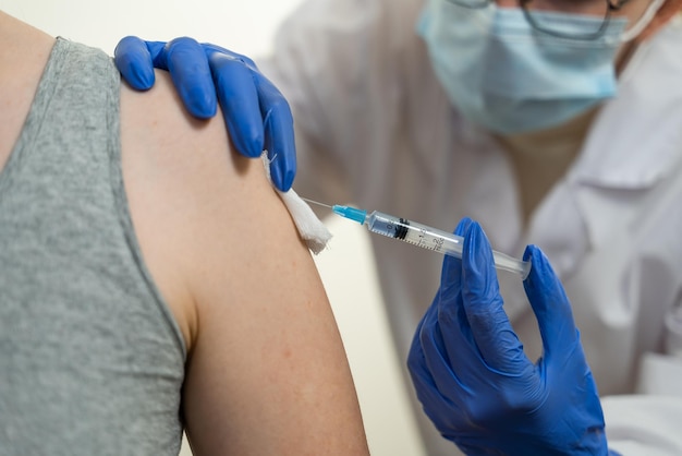 The doctor vaccinates the patient in the shoulder. Syringe, bandage, antiseptic. A typical day at the hospital.