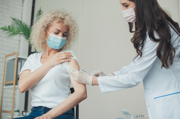 Doctor vaccinating female patient in clinic healthcare concept coronavirus immunization flu treatmen