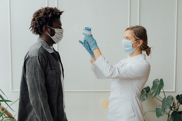 A doctor wearing a mask and gloves holds a test tube to a man.