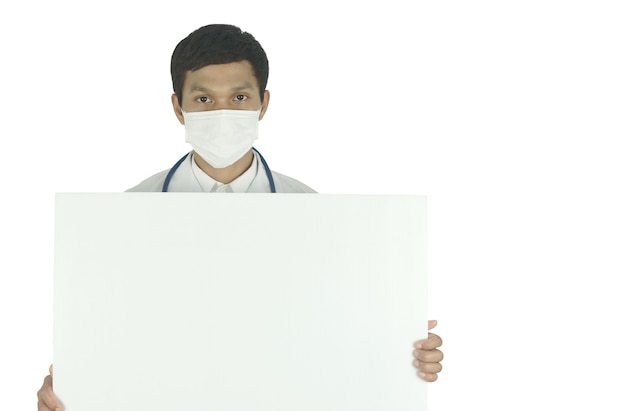 Doctor wearing medical mask with stethoscope holding white billboard and copy space