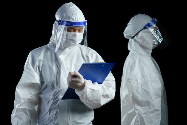 Doctor wearing PPE and face shield holding corona/covid-19 virus laboratory report in hands.