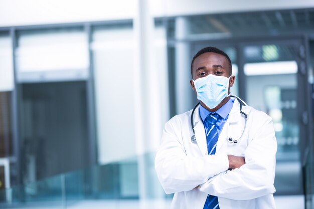 Doctor wearing surgical mask standing with hands crossed