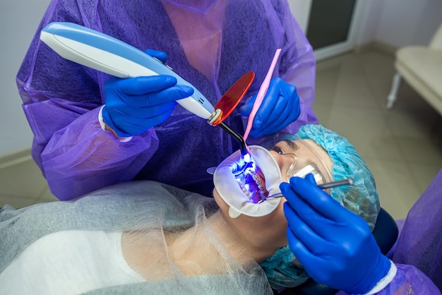 Doctor with an assistant in a protective suit and goggles using UV lamp makes procedure