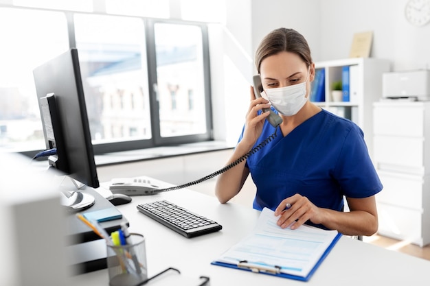 Photo doctor with computer calling on phone at hospital