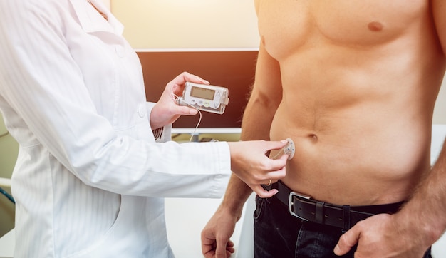 Doctor with an insulin pump connected in patient abdomen