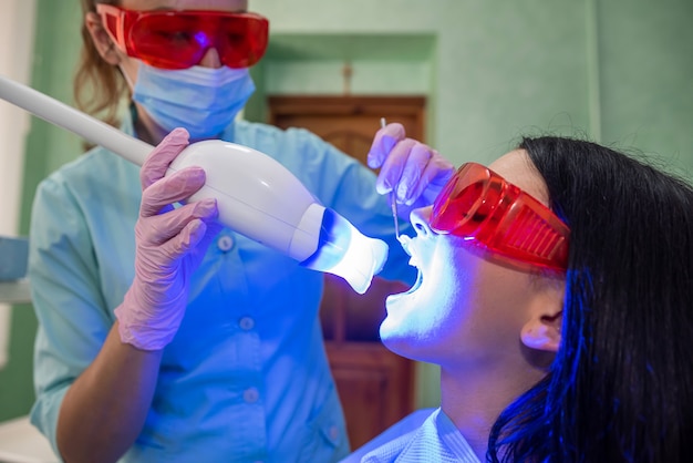 Doctor with lamp and mirror treating patients teeth close up