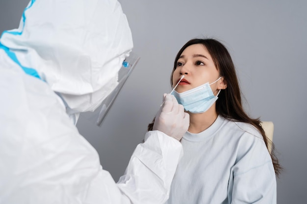 Doctor with PPE suit test coronavirus(covid-19) to young woman by nasal swab