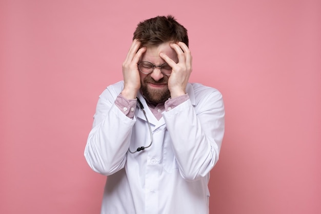 Doctor with a stethoscope around neck is stressed or has a severe headache