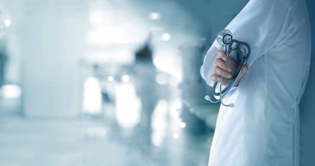 Doctor with stethoscope in hand on hospital background, medical and medicine concept