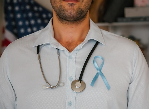 Doctor with a stethoscope on his neck and a blue ribbon writing Man prostate cancer awareness month