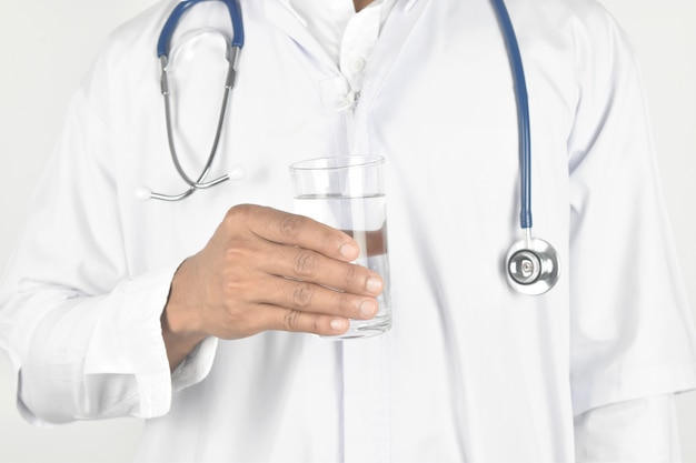 Doctor with stethoscope holding glass of water.