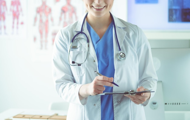 Doctor with a stethoscope holding a notebook in his hand closeup of a female doctor filling up medic