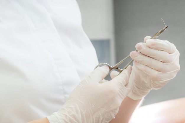 Doctor with surgical forceps holding a suture needle