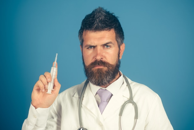 Doctor with syringe on blue background. Male doctor preparing syringe. Treatment in hospital, antibiotics. Concept health.