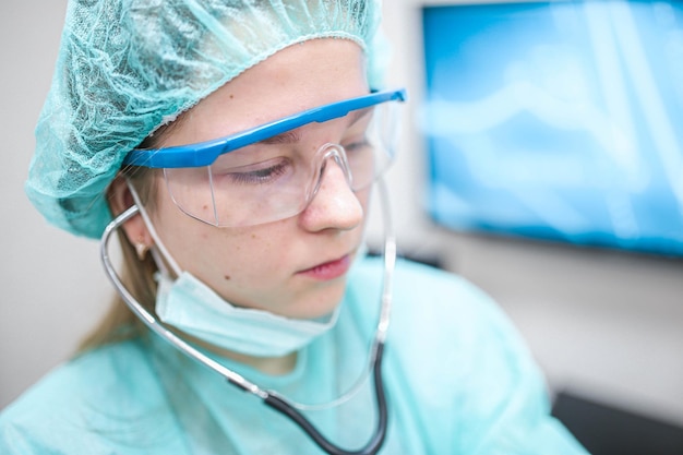 doctor woman in the hospital listens to the patient with a stethoscope