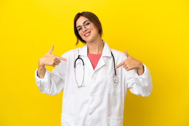 Doctor woman isolated on yellow background proud and self-satisfied