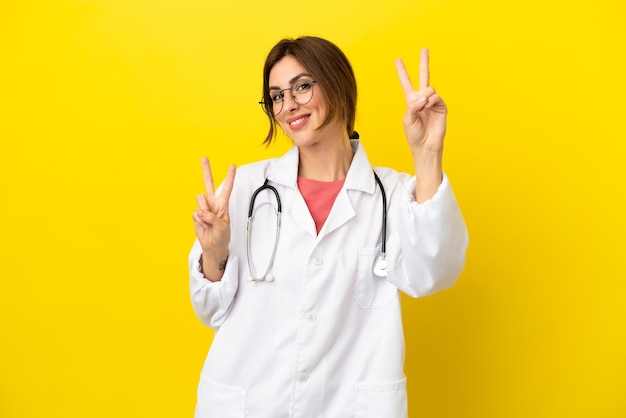 Doctor woman isolated on yellow background showing victory sign with both hands