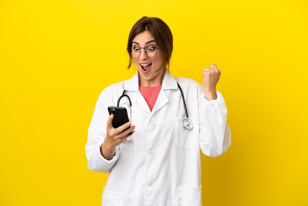 Doctor woman isolated on yellow background surprised and sending a message