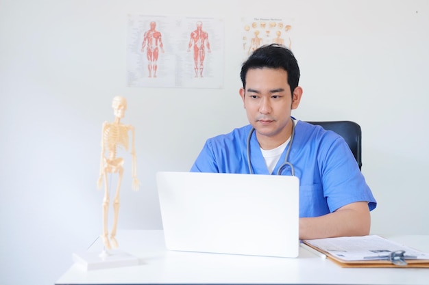 Doctor working on laptop at the desk in clinic.