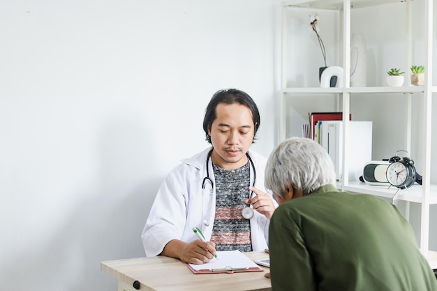 Doctor writing medical prescriptions for senior patient at the clinic.