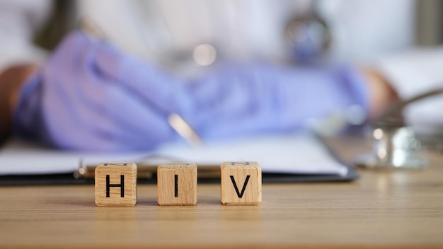 Doctor writing out prescription against background of wooden cubes with word hiv closeup