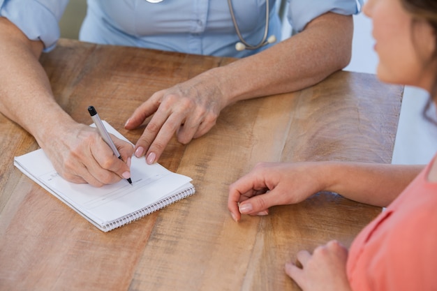 Doctor writing a prescription for her patient in medical office