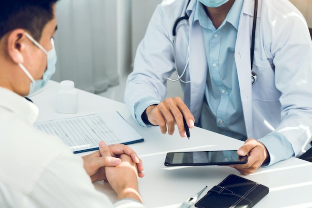 Doctors are explaining the treatment of a sick patient in tablets while wearing a mask during the virus outbreak