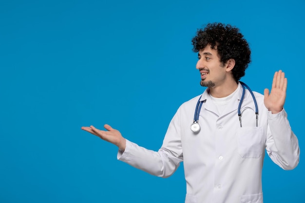 Doctors day curly handsome cute guy in medical uniform waving hands happily