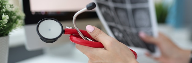 Doctors hands are holding stethoscope and pictures of brain