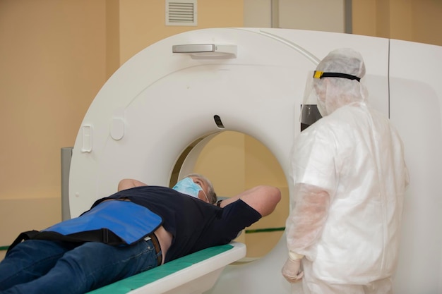 Doctors in protective medical suits are doing an MRI scan to a patient with coronavirus infection.