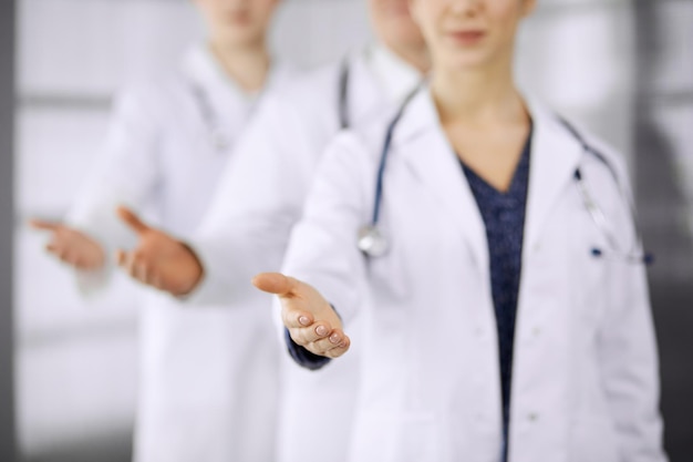 Doctors standing as a team while offering helping hand for shaking hand or saving life in clinic.