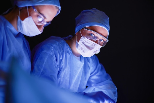 Doctors team in surgery in a dark background