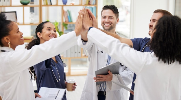 Photo doctors teamwork and high five in meeting motivation or success in healthcare together at hospital happy group of medical professionals touching in team building support or goals at the clinic