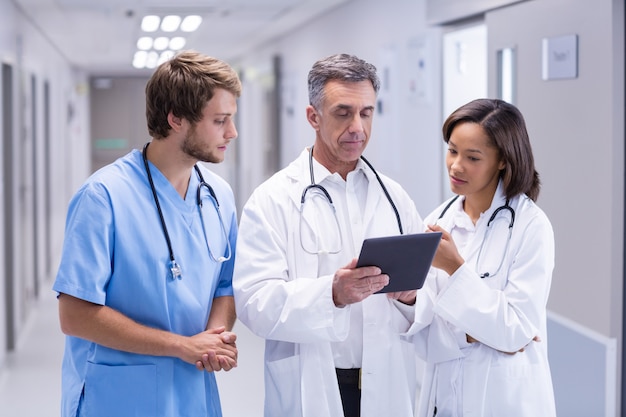 Doctors using digital tablet in corridor