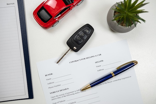 Document automobile insurance policy or sale with pen and red toy car key at office desk