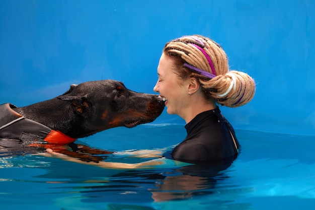 Dog trainer at the swimming pool teaching the dog to swim