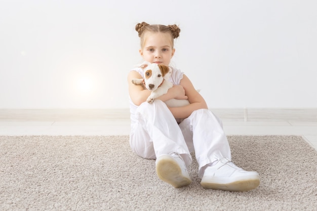 Dogs, pets and animal concept - Little child girl sitting with puppy Jack Russell Terrier