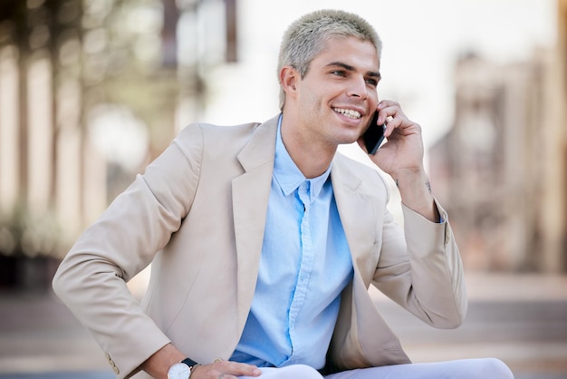 Doing business on the go. Shot of a handsome young businessman sitting alone and using his cellphone in the city.