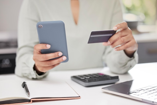 Doing her business online High angle shot of an unrecognizable businesswoman using her cellphone while holding a credit card in the office