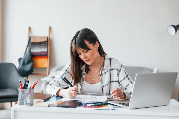 Doing paperwork Young female freelance worker is indoors in home at daytime