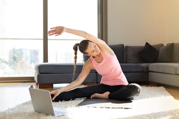 doing yoga exercises in front of the laptop