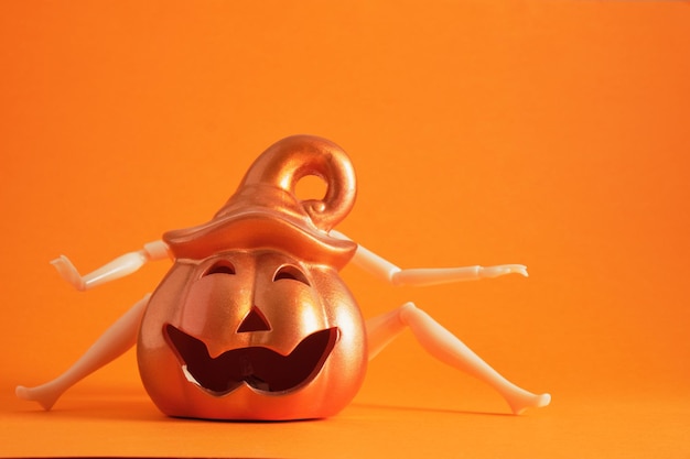 Doll and decorative ceramic pumpkin lantern on orange background kopi space halloween concept