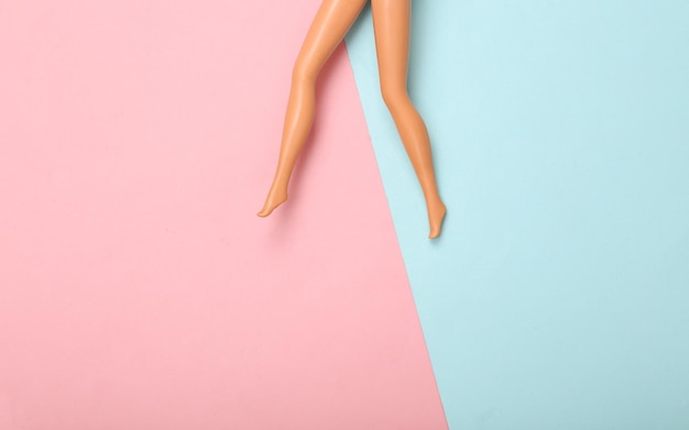 Doll female bare feet on a bluepink pastel background Creative minimalistic layout