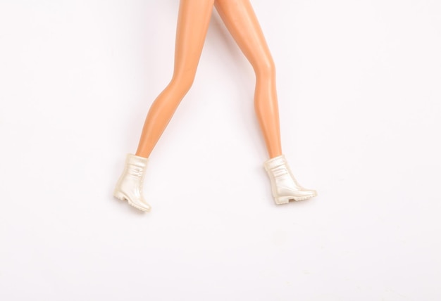 Doll female legs in boots on white background Creative minimalistic layout