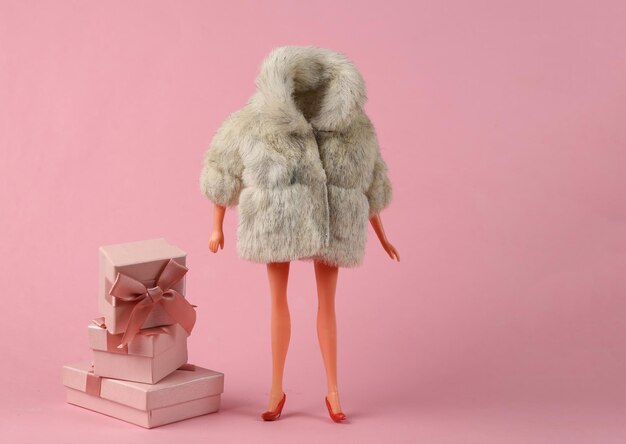 Doll mannequin in warm fur coat with gift boxes on pink background Minimalism holiday concept Concept art