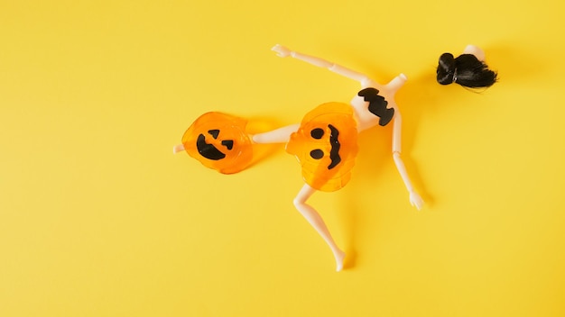 Doll and silicone pumpkins on yellow background